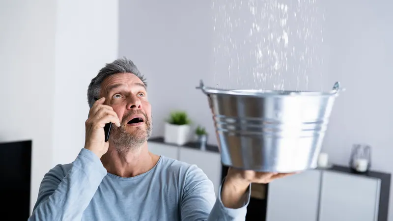 Homeowner catching water dripping from a ceiling leak