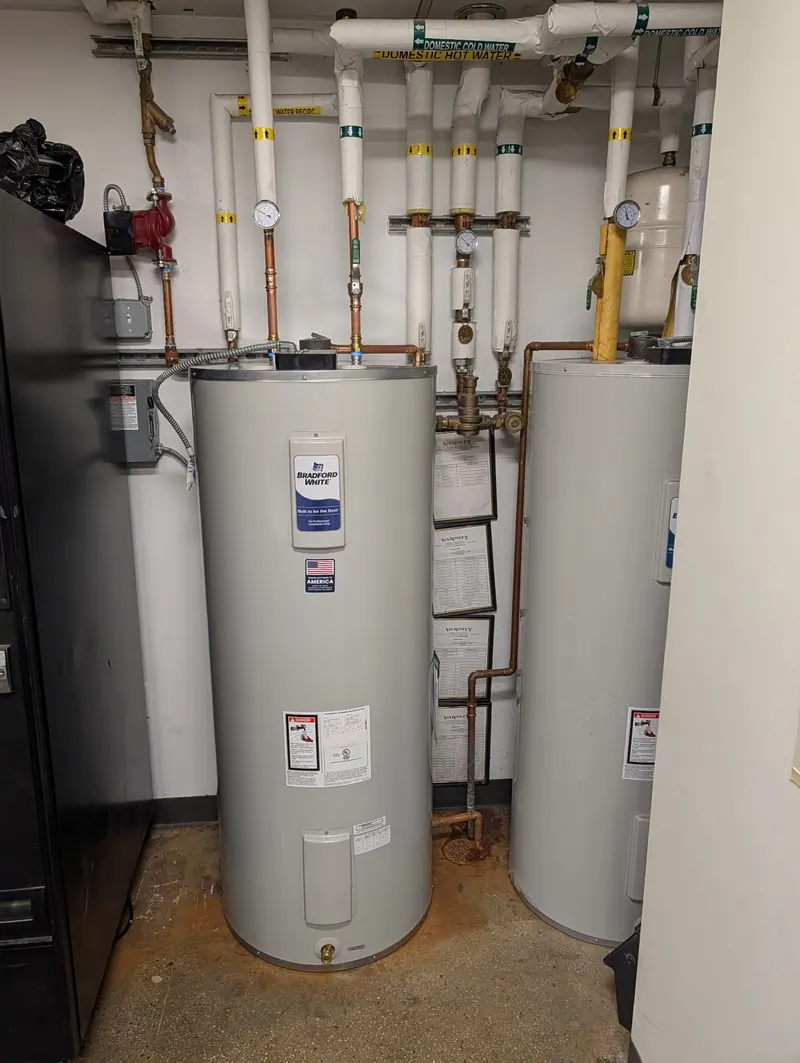 Two new tank water heaters side by side in a commercial mechanical room installed by Fullerton