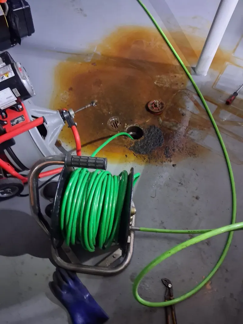 Fullerton drain cleaning machine with cable running into a backed up basement floor drain