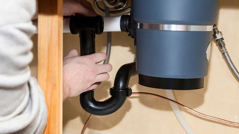 Garbage disposal being installed under a kitchen sink
