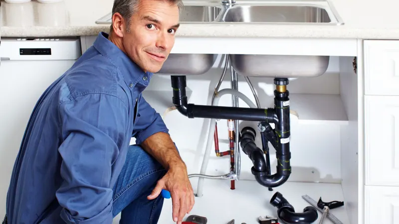 Fullerton plumber checking the drain pipes under a kitchen sink in a New York home