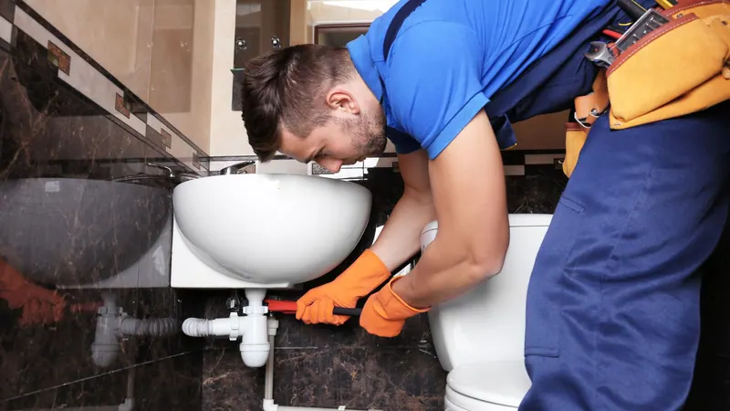 Plumber repairing a toilet and bathroom sink